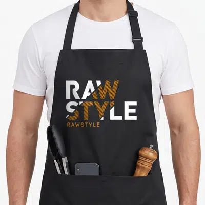 Tablier de cuisine noir avec le logo Rawstyle en lettres blanches et oranges stylisées.