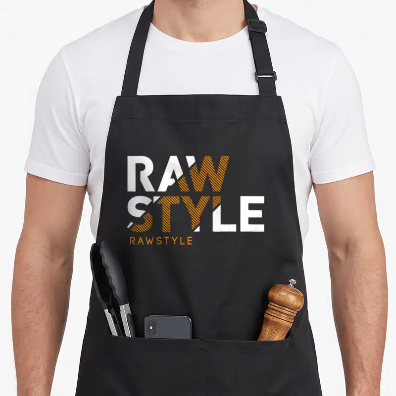 Tablier de cuisine noir avec le logo Rawstyle en lettres blanches et oranges stylisées.