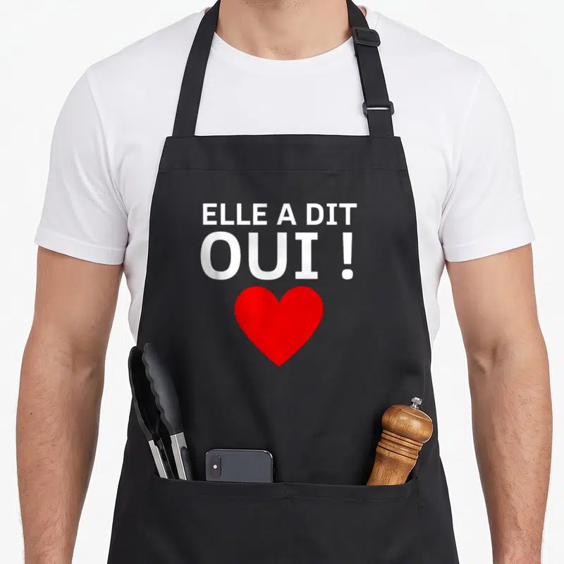 Tablier de cuisine noir avec texte blanc Elle a dit OUI et un grand cœur rouge en dessous.