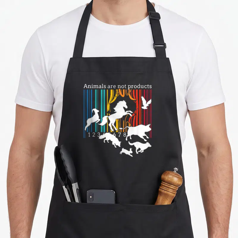 Tablier de cuisine noir avec un code-barres multicolore et des silhouettes animales blanches en mouvement sous le texte Animals are not products.