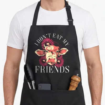 Tablier de cuisine noir avec tête de vache rouge et texte Je ne mange pas mes amis en blanc.