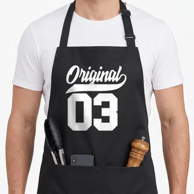Tablier de cuisine noir avec l'inscription Original 03 en typographie blanche vintage.