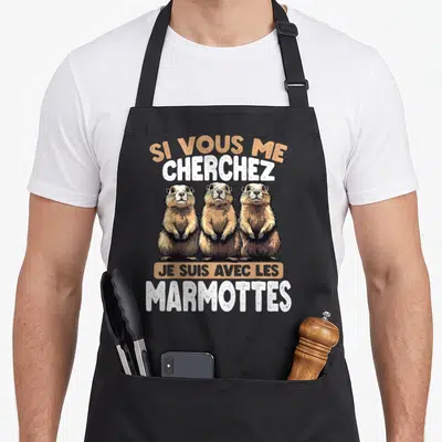 Tablier de cuisine noir orné de trois marmottes marron et du message Si Vous Me Cherchez Je suis avec Les Marmottes en lettres blanches et orange.