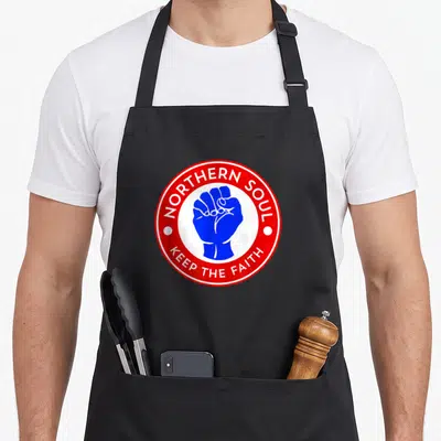 Tablier de cuisine noir avec logo circulaire Northern Soul Keep The Faith poing bleu et texte rouge.