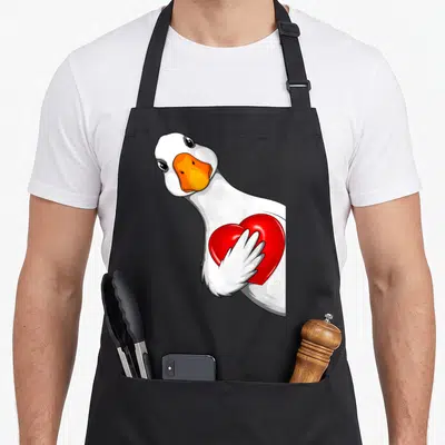 Tablier de cuisine noir avec une illustration d'une oie blanche tenant un cœur rouge brillant contre sa poitrine.