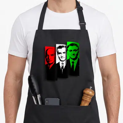 Tablier de cuisine noir avec trois portraits masculins en rouge, blanc et vert sur fond uni.