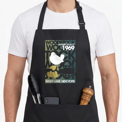 Tablier de cuisine noir avec illustration vintage woodstock 1969 montrant une colombe blanche et le texte white lake new york.