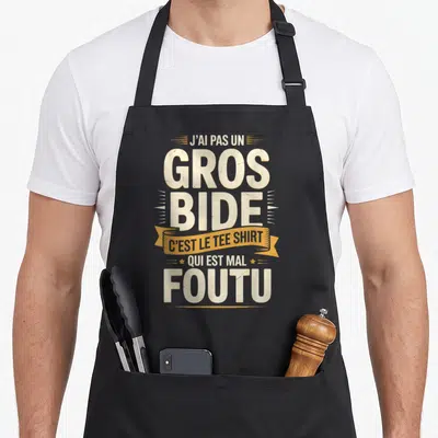 Tablier de cuisine noir avec inscription humoristique en blanc et jaune sur fond uni.