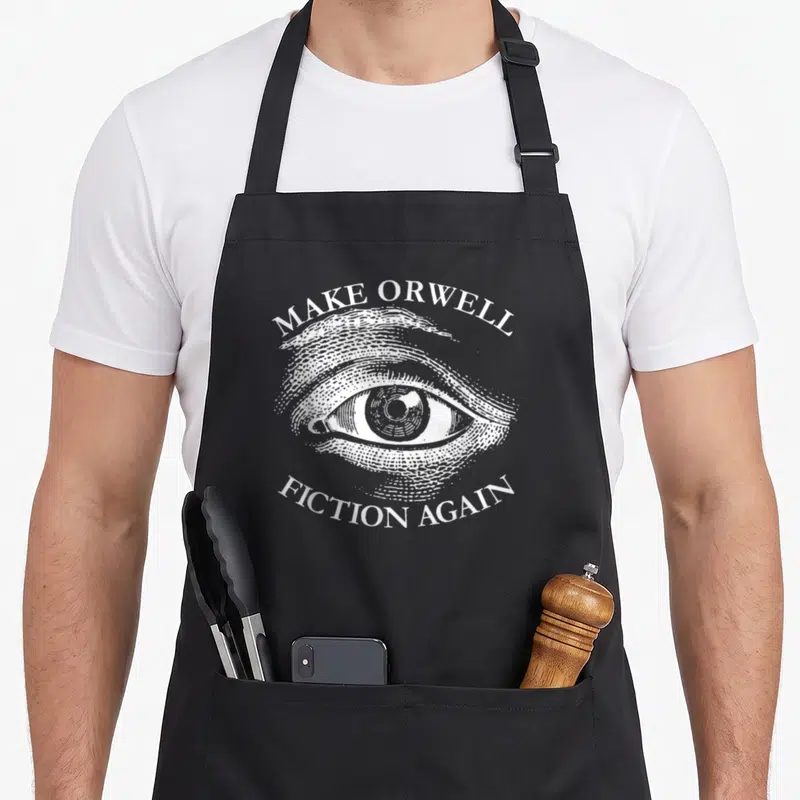 Tablier de cuisine noir avec un grand œil gravé et le texte Make Orwell Fiction Again en blanc.