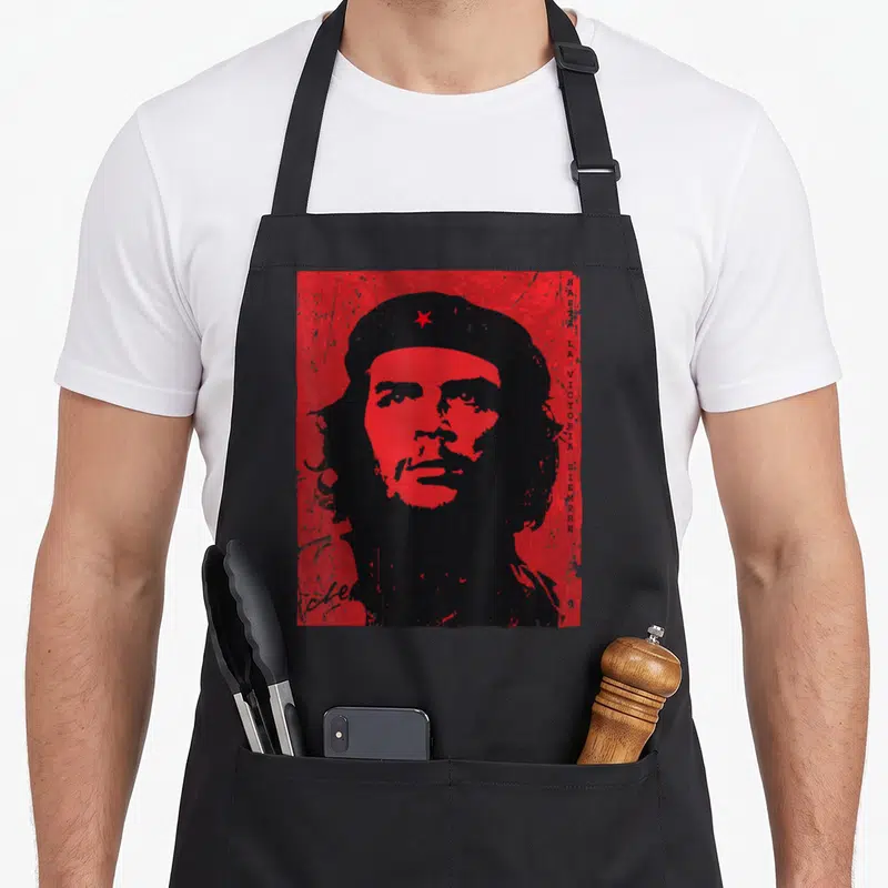 Tablier de cuisine noir avec portrait stylisé en rouge de Che Guevara et texte vertical Hasta la victoria siempre sur le côté droit.