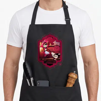 Tablier de cuisine noir avec illustration colorée de Niffty en tenue de servante et un petit démon noir dans un cadre décoratif rose.