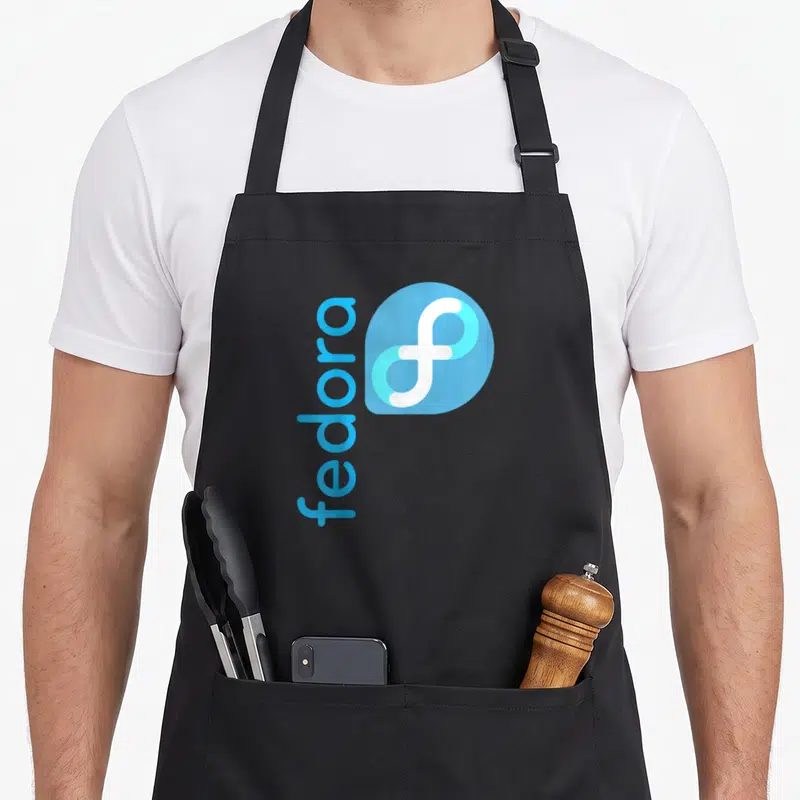 Tablier de cuisine noir avec le logo Fedora Open Source Os en bleu clair et blanc imprimé au centre du torse.