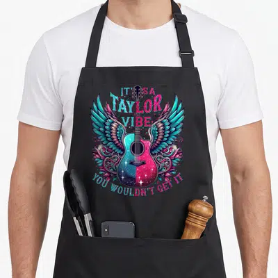 Tablier de cuisine noir avec une guitare aux ailes turquoise et roses et du texte en anglais.