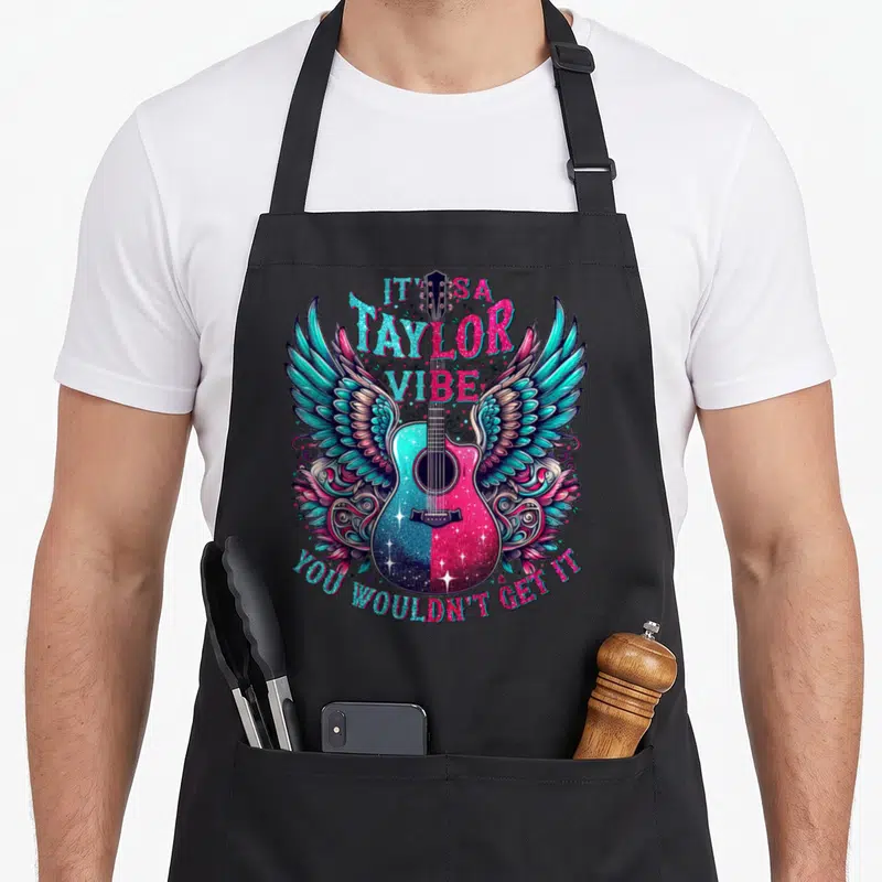 Tablier de cuisine noir avec une guitare aux ailes turquoise et roses et du texte en anglais.