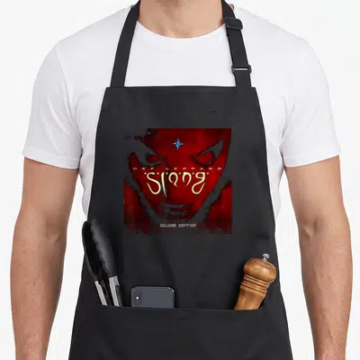 Tablier de cuisine noir avec illustration rouge et dorée de l'album Slang de Def Leppard incluant un visage stylisé et une étoile bleue.