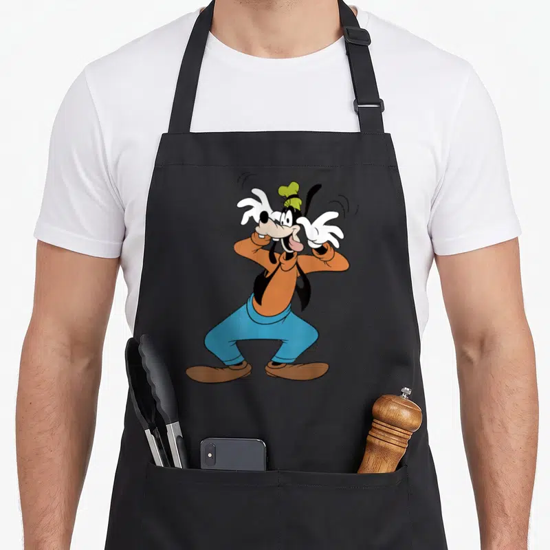 Tablier de cuisine noir avec Goofy en train de s'exciter, portant une toque verte et les mains dans les cheveux.