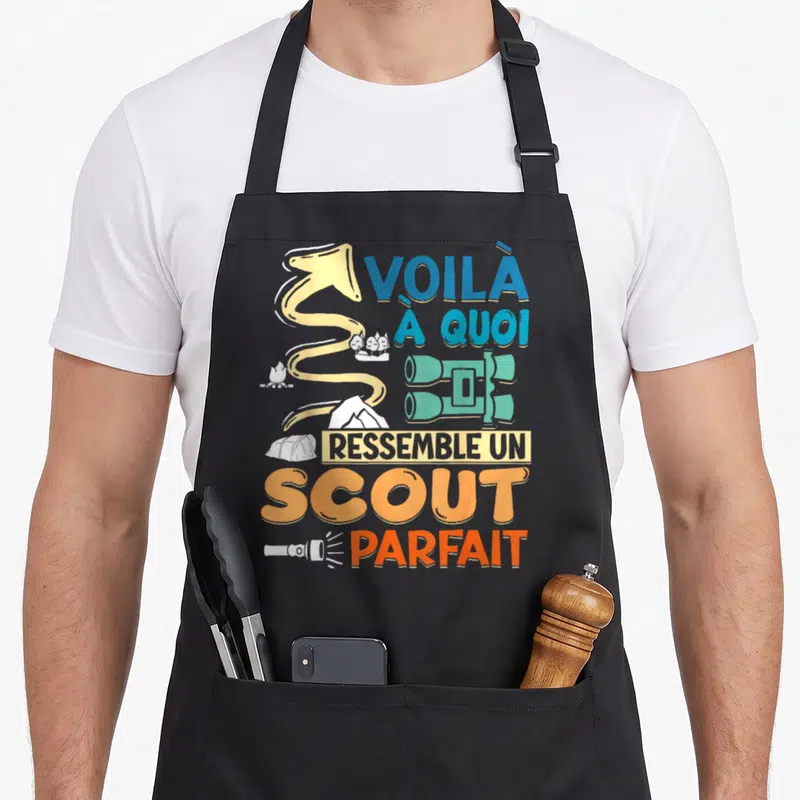 Tablier de cuisine noir avec illustration de boussole, tente, jumelles et texte orange bleu.