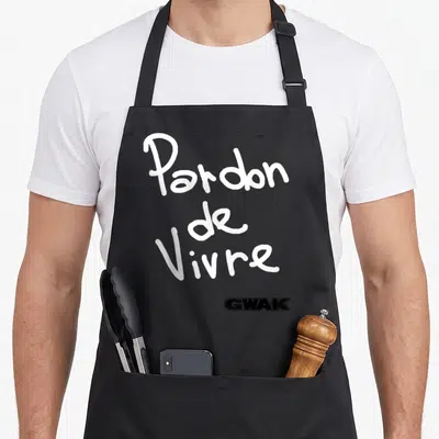 Tablier de cuisine noir avec l'inscription Pardon de Vivre en écriture manuscrite blanche et le logo GWAK en bas à droite.