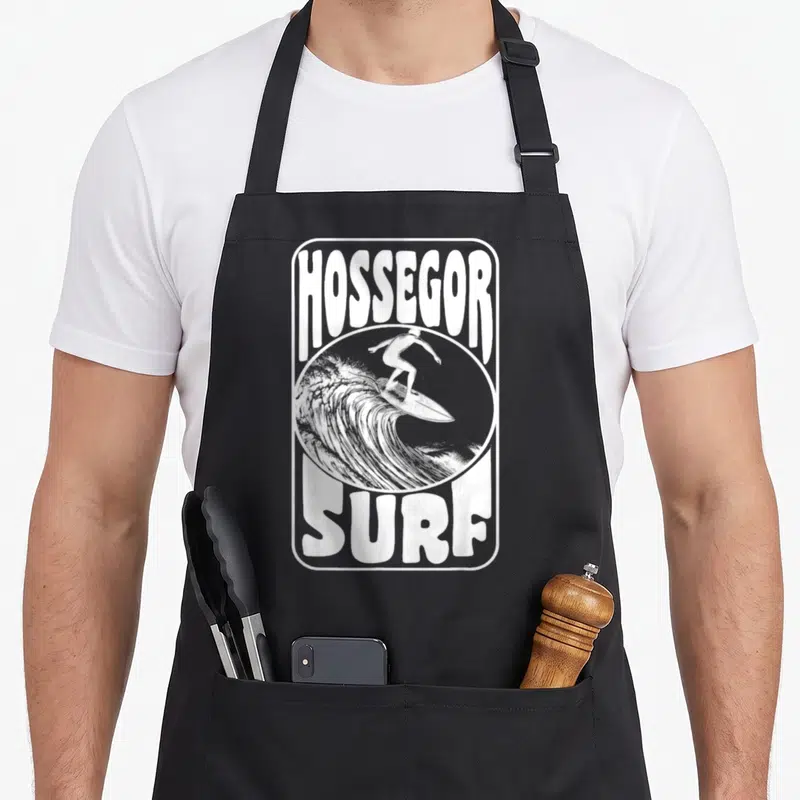 Tablier de cuisine noir avec illustration blanche d'un surfeur et du texte Hossegor Surf encadré.