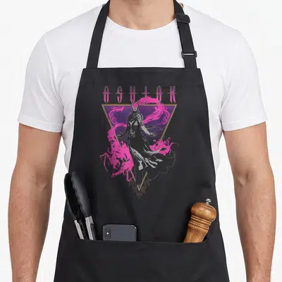 Tablier de cuisine noir avec une silhouette fantomatique grise, des nuages roses et le nom ASHIOK en lettres stylisées violettes.