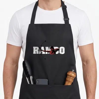Tablier de cuisine noir avec silhouette rouge tirant à l'arc devant le texte RAMBO en blanc texturé.