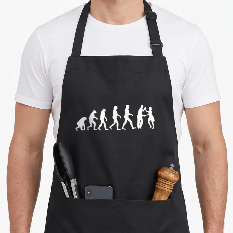 Tablier de cuisine noir avec une illustration blanche représentant l'évolution humaine jusqu'à un couple dansant le West Coast Swing.