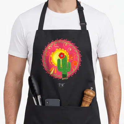Tablier de cuisine noir avec illustration circulaire rose, cactus vert, soleil jaune et signature FK en bas.