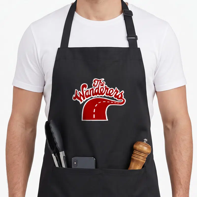 Tablier de cuisine noir avec le logo The Wanderers en rouge sur une route sinueuse blanche.