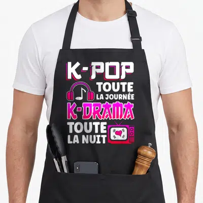 Tablier de cuisine noir avec inscription K-pop toute la journée K-drama toute la nuit en rose et blanc, illustré d'un casque et d'une télévision.