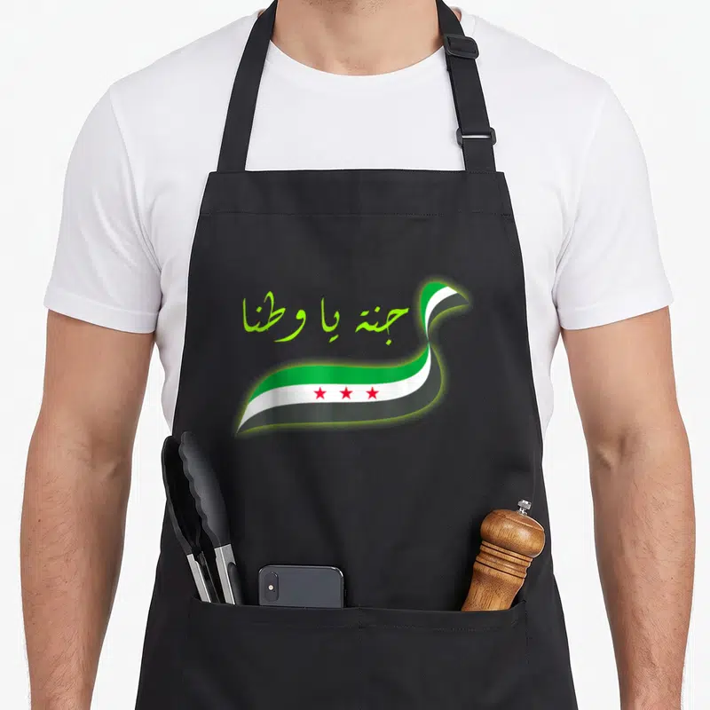 Tablier de cuisine noir avec drapeau syrien ondulé et inscription arabe verte lumineuse.