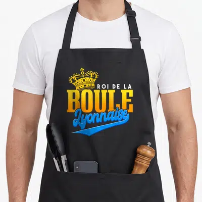 Tablier de cuisine noir avec une couronne dorée et l'inscription roi de la boule lyonnaise en orange et bleu.