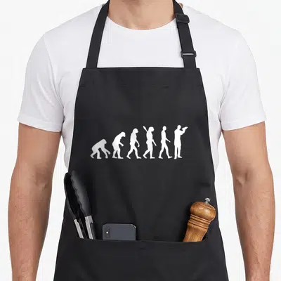 Tablier de cuisine noir avec illustration blanche de l'évolution humaine se terminant par une silhouette de barman tenant un shaker.