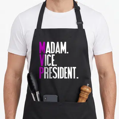 Tablier de cuisine noir avec inscription Madam Vice President en lettres blanches et magentes stylisées.