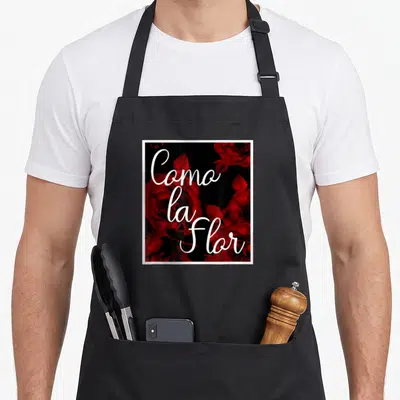 Tablier de cuisine noir avec des roses rouges et l'inscriptionComo la Floren blanc au centre.