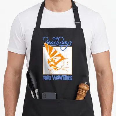 Tablier de cuisine noir avec illustration orange d'un windsurfer et texte bleu The Beach Boys Good Vibrations.