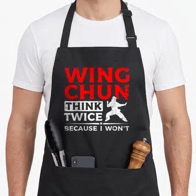 Tablier de cuisine noir avec le texte Wing Chun pense deux fois et une silhouette de combattant en position de garde.
