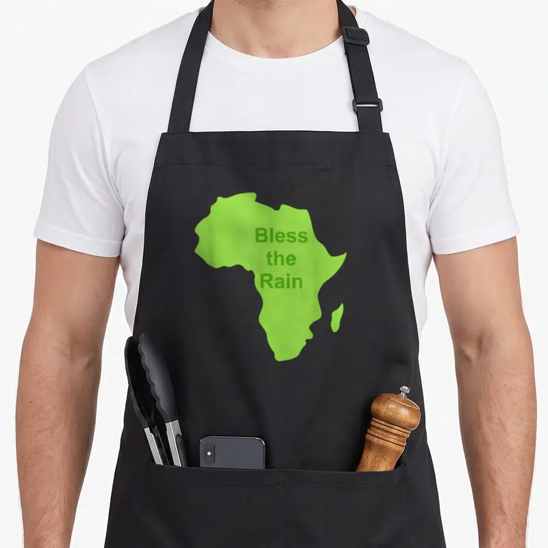 Tablier de cuisine noir avec une carte verte de l'Afrique et le texte Bless the Rain imprimé au centre.