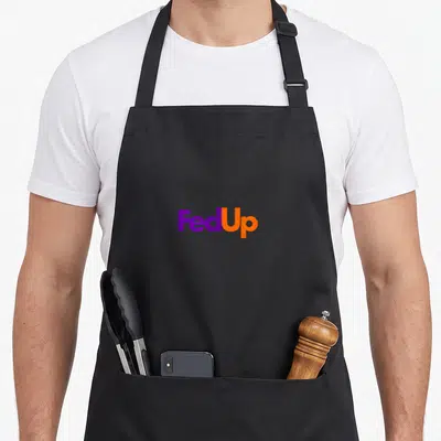 Tablier de cuisine noir avec le logo Fed Up imprimé en violet et orange au centre.