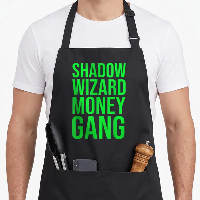 Tablier de cuisine noir avec l'inscription verte en majuscules Shadow Wizard Money Gang disposée verticalement.