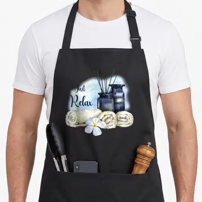 Tablier de cuisine noir avec serviettes roulées, diffuseurs bleus et fleur blanche au centre du motif.