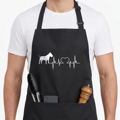 Tablier de cuisine noir avec silhouette Bull Terrier et ligne cardiologique blanche formant un cœur.