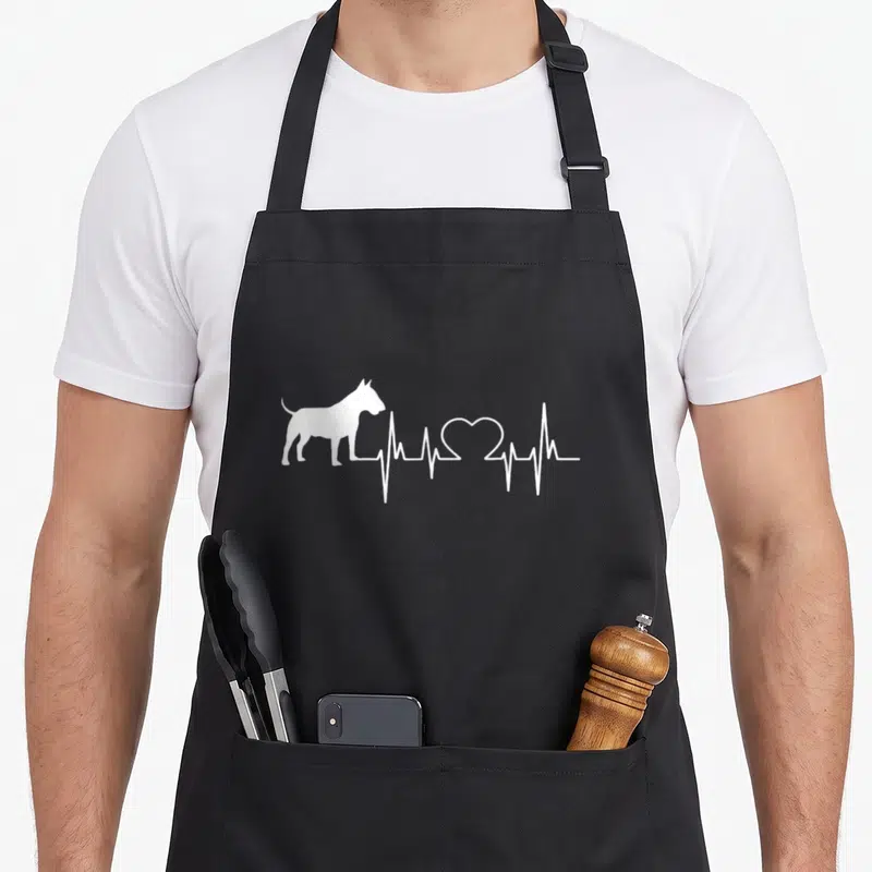 Tablier de cuisine noir avec silhouette Bull Terrier et ligne cardiologique blanche formant un cœur.