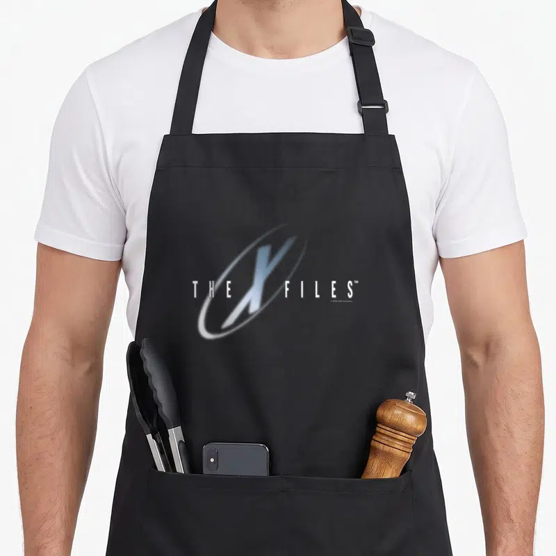 Tablier de cuisine noir avec le logo The X-Files en blanc et bleu sur fond gris uni.