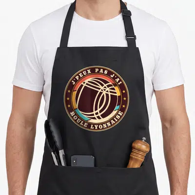 Tablier de cuisine noir avec un logo circulaire vintage représentant une boule de Lyonnaise et des étoiles dorées.