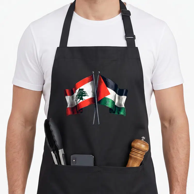 Tablier de cuisine noir avec drapeaux du Liban et de la Palestine croisés en illustration gravée.