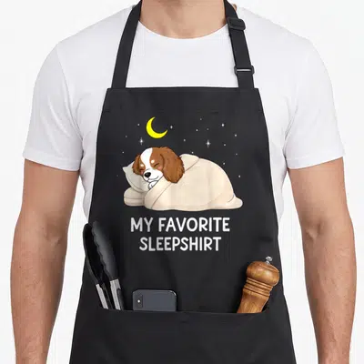 Tablier de cuisine noir avec un chien Cavalier King Charles Spaniel dormant sous une couette et le texte My Favorite Sleepshirt.