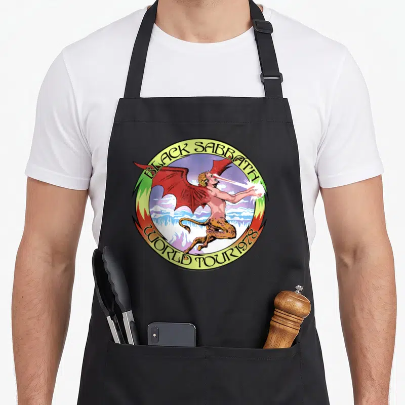 Tablier de cuisine noir avec logo circulaire Black Sabbath World Tour 1978 et illustration de démon ailé crachant un rayon.