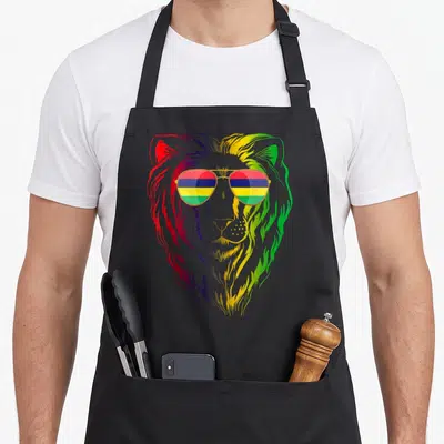 Tablier de cuisine noir avec illustration d'un lion aux couleurs vives portant des lunettes aviateur.