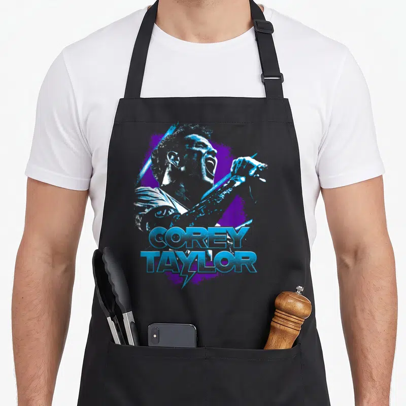 Tablier de cuisine noir avec une illustration bleue et violette de Corey Taylor tenant un micro et son nom imprimé en dessous.