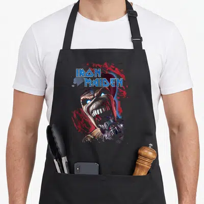 Tablier de cuisine noir avec illustration d'Eddie et le logo Iron Maiden en lettres bleues.